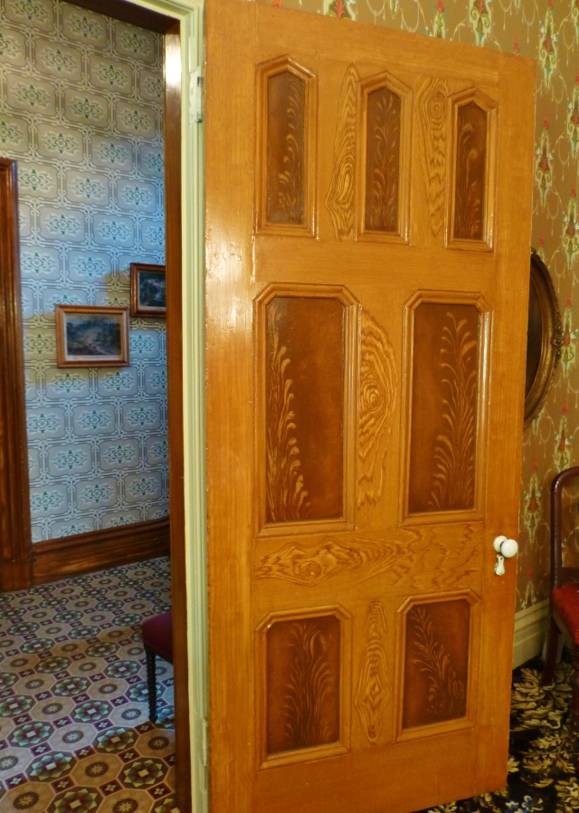 Much of the woodwork in the house, including the doors in the dining room are hand-painted faux wood grain.  If you look closely you can see that various colors of brown, caramel and gold paint have been used to simulate more expensive wood grain patterns.  This was a popular thing to do in middle class homes of the Victorian era. Doesn't it look so real?