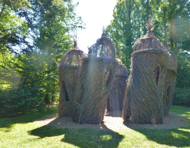 According to the Morris Arboretum Website: "In the last thirty years, Dougherty has created some 260 sculptures in more than 15 countries. A Waltz in the Woods includes seven “towers”, each roughly 30 feet high, through which visitors may roam. Open windows create an airy feel, and opposing doors allow for travel between the towers. The variations in shape and size create a unique sense of flow and a maze-like feel. The negative space within the circle of the towers pays homage to the Arboretum’s Summer Palace which Dougherty created in 2009."
